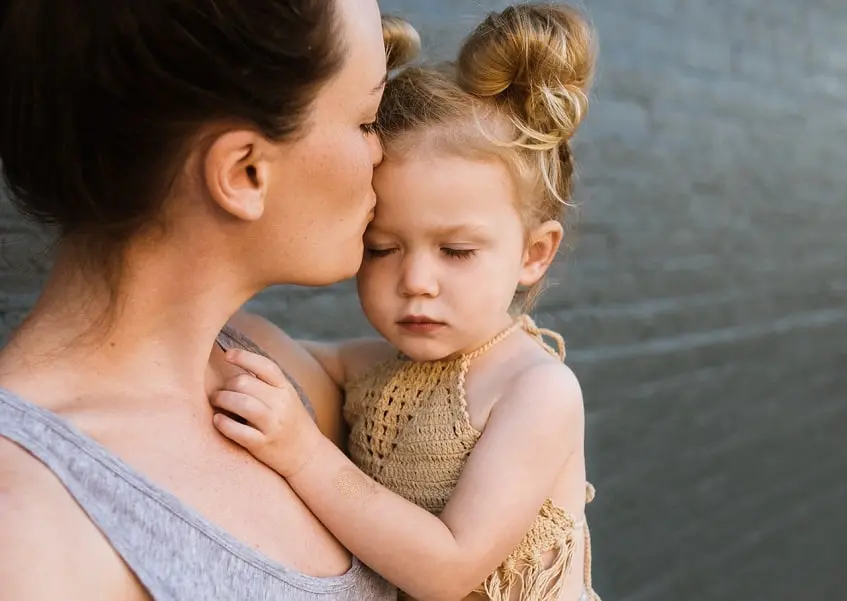 mujer besando a niña en su frente
